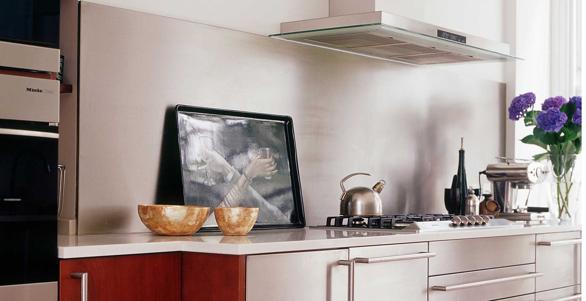 contemporary kitchen with red and stainless steel cabinets with a stainless steel splashback to support the stainless steel kitchen trend for 2024