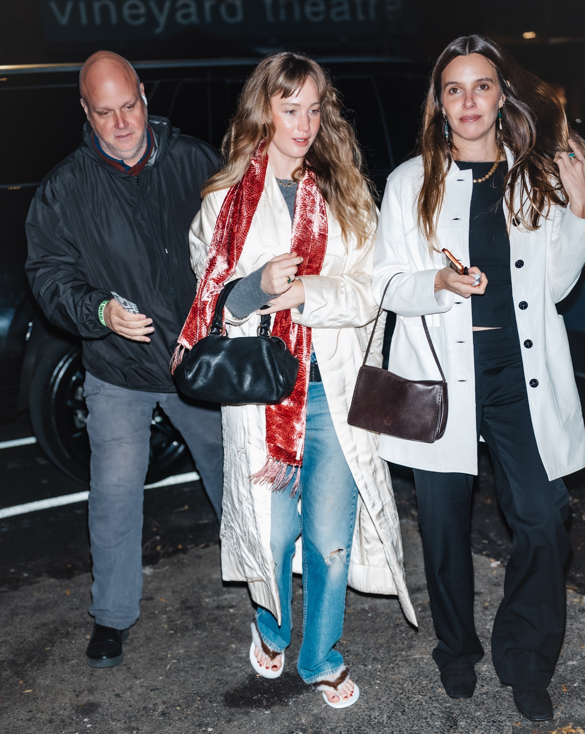 Jennifer Lawrence wore a velvet scarf, a white coat, jeans, and furry flip-flops to a concert in NYC