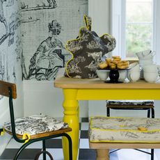 yellow dining table with chairs and grey wallpaper on wall