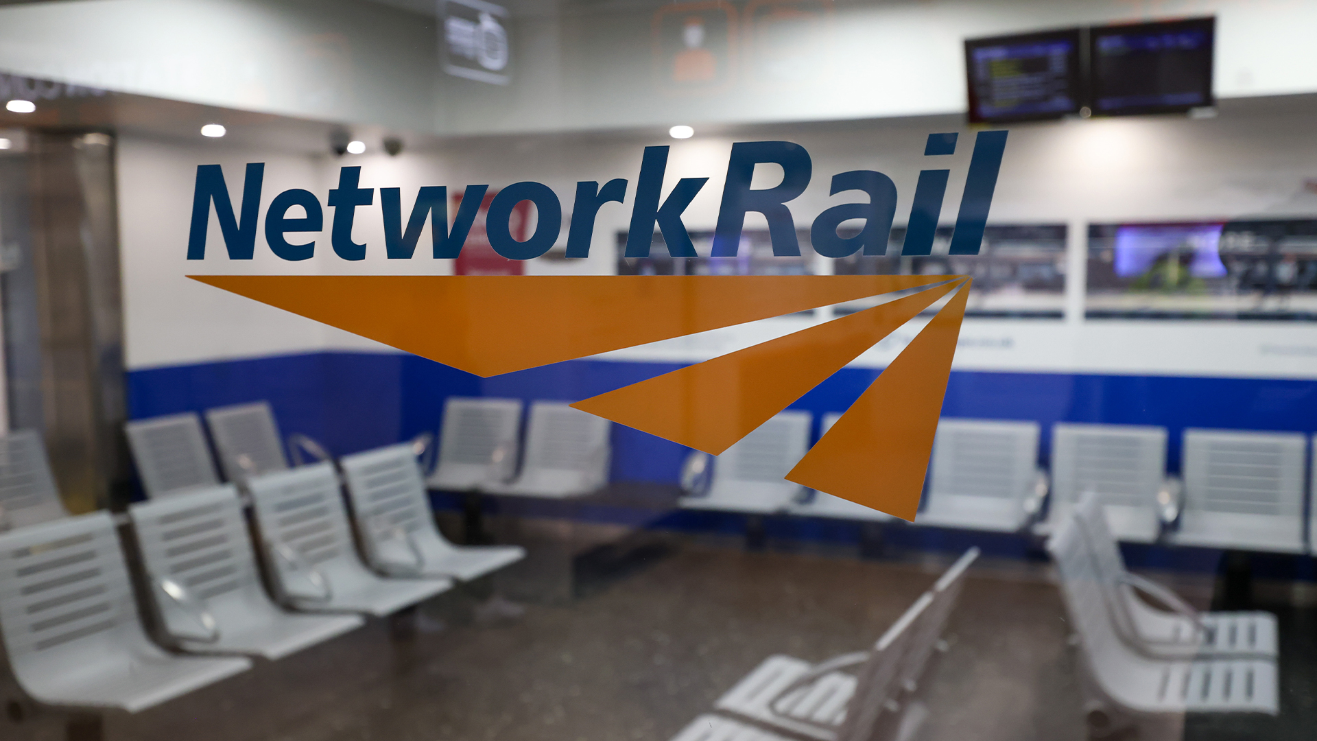 Network Rail logo and branding pictured on a glass partition at a waiting room in London Euston railway station.