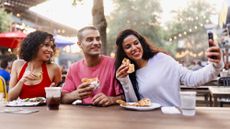 Friends sitting around a table at a food festival, taking a selfie.