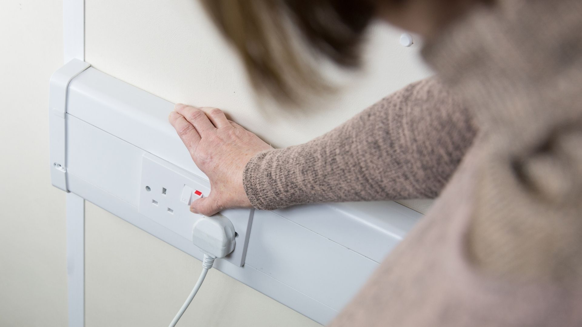 picture of woman turning on plug in wall