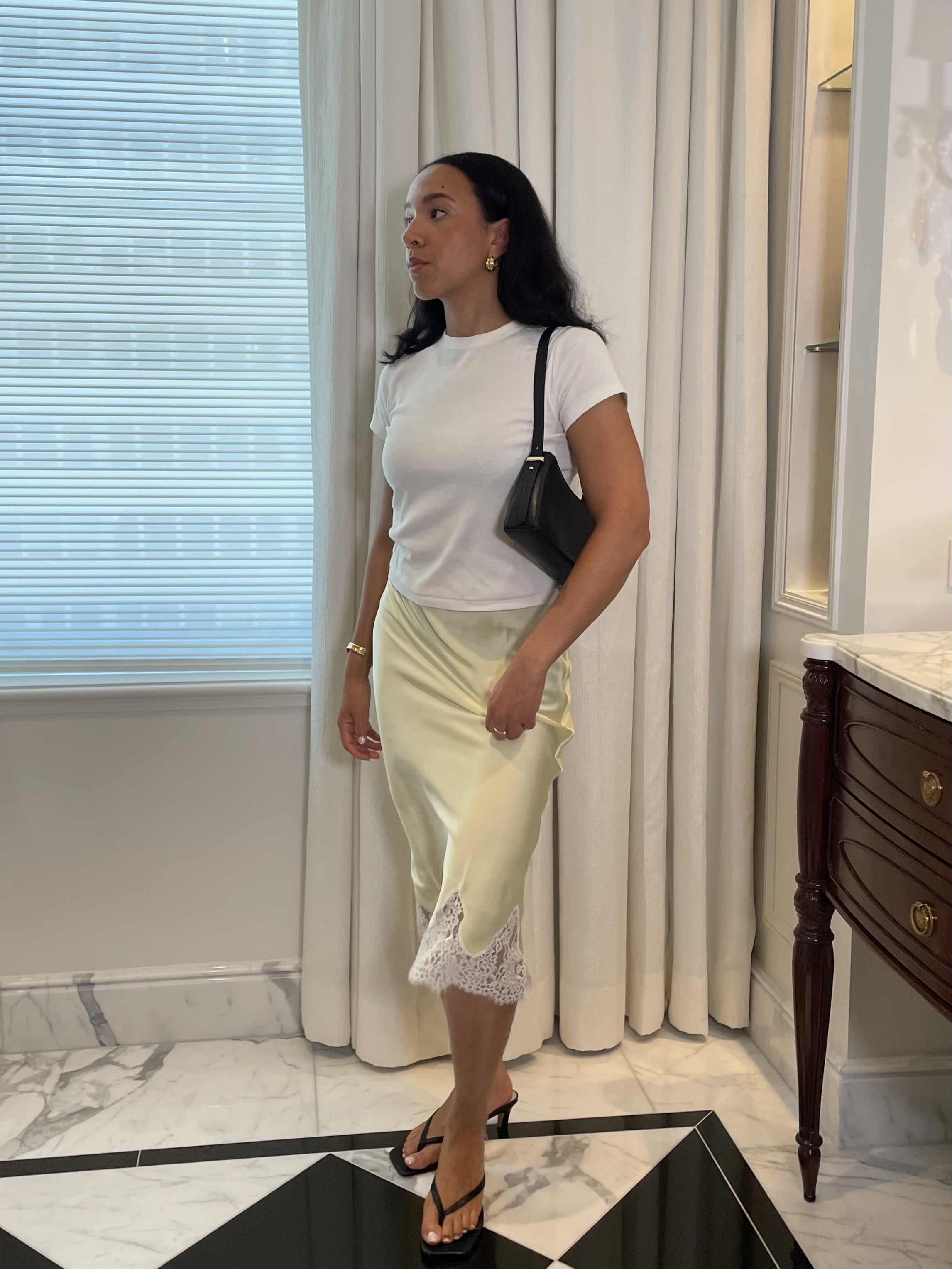 Lauren Tappan wearing a white tee, a yellow lace skirt, and black sandals