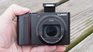 A hand holding the best travel camera the Panasonic Lumix ZS200