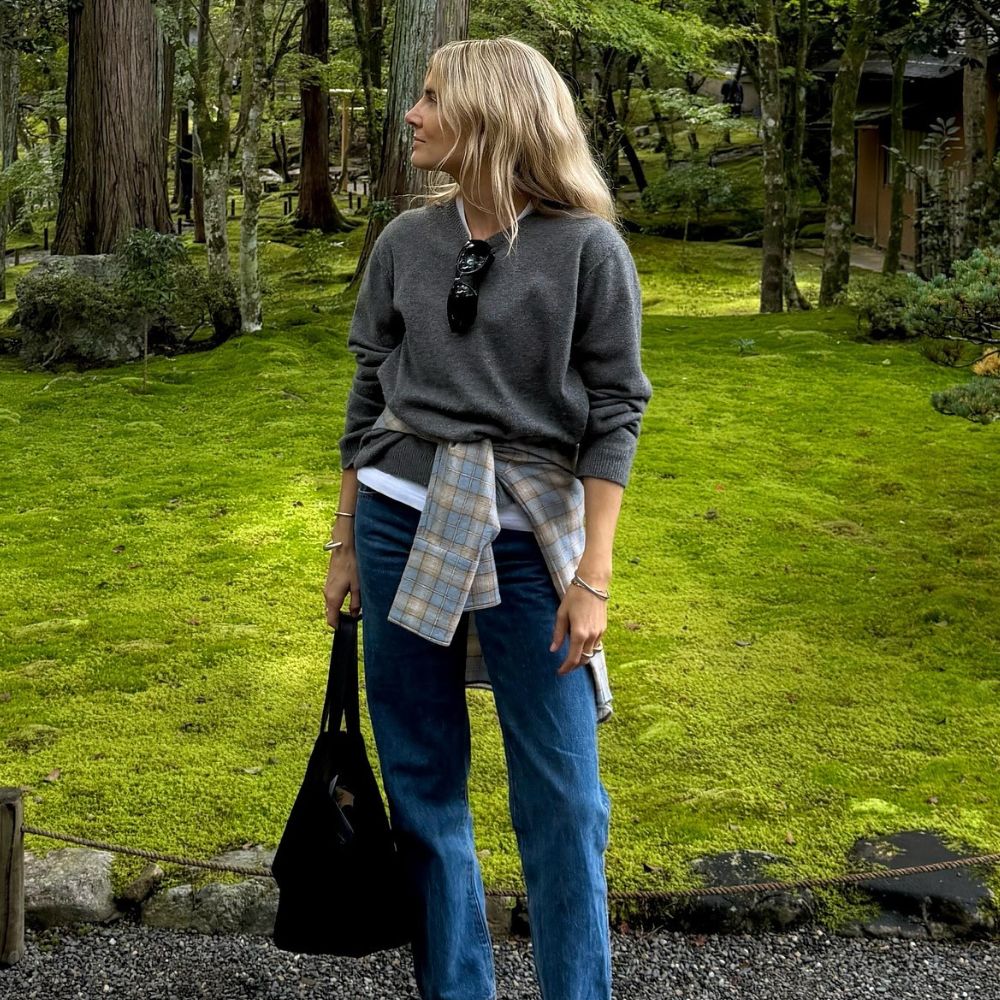 Influencer @lucywilliams02 wears stove pipe jeans with orange trainers, a grey knit and a shirt tied around her waist.