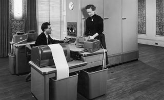 Black and white photo of man and lady working on an old computer