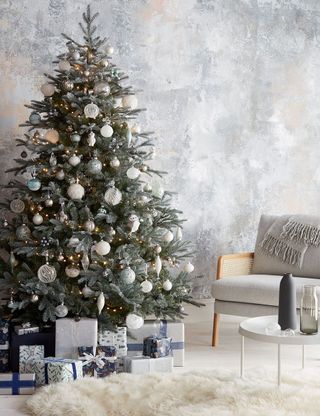 room with christmas tree gift boxes and armed chair with cushions