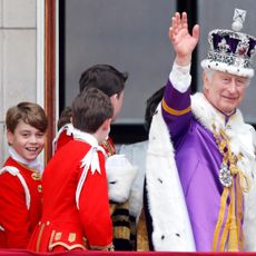 King Charles waving in his coronation crown and cape with Prince George smiling next to him