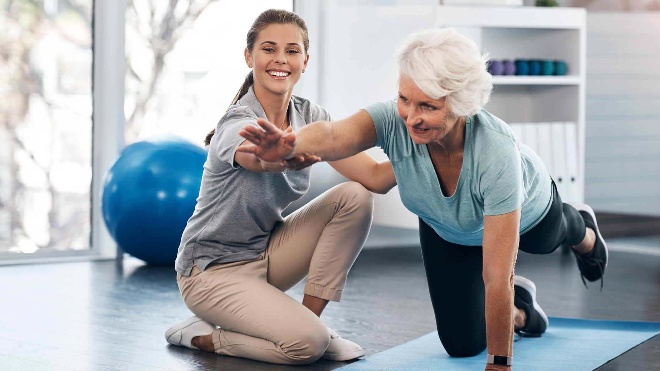 Senior woman exercising under the supervision of a trainer