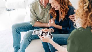 Expectant parents meet with a surrogate who is holding sonogram photos.