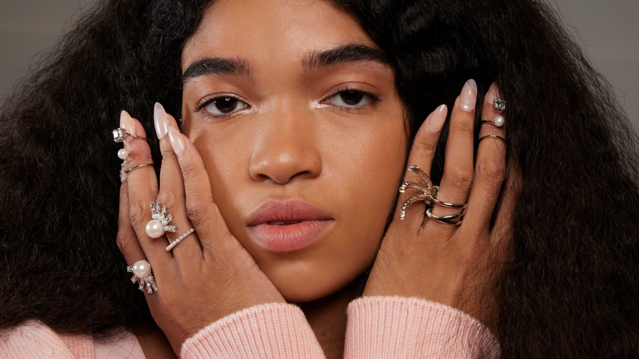 A model holding up her nails with rings around her face backstage at the Adeam S23 show 