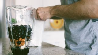 Man prepares protein shake at home in blender