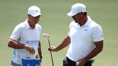 Brooks Koepka hands his caddie his putter