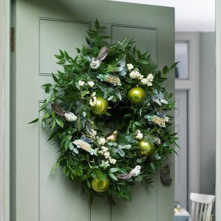 Green front door with green christmas wreath with car and dove ornaments and green baubles
