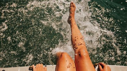 Best body shimmer - woman splashing legs in the sea