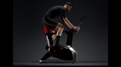 Wattbike Atom review: Pictured here, a young man riding the exercise bike in a dark photo studio