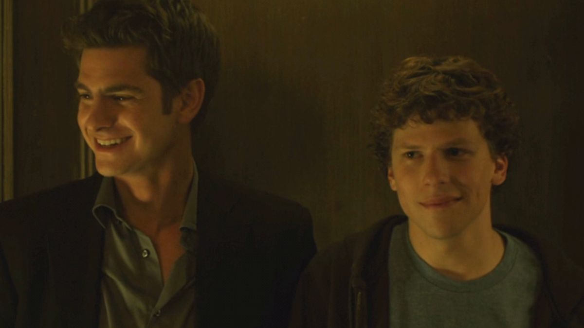 Andrew Garfield and Jesse Eisenberg smile together while hanging out in The Social Network.