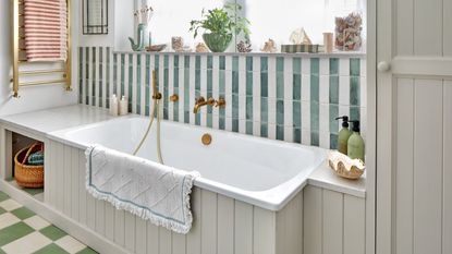 Bathroom with panelled bath and green and white striped tiles