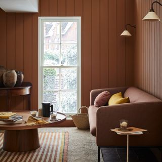 A brown-painted living room with vertical wood wall panelling and a tonal sofa