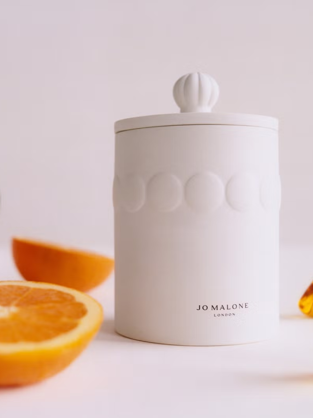 A golden amber and orange ceramic candle with a lid