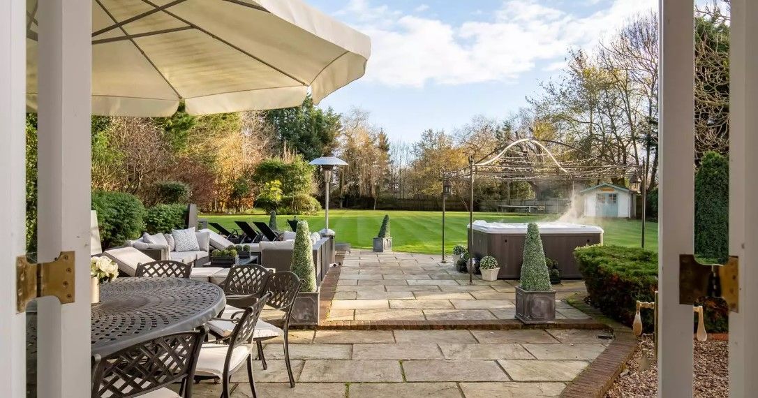 The patio shows a hot tub, seating area and large grass garden