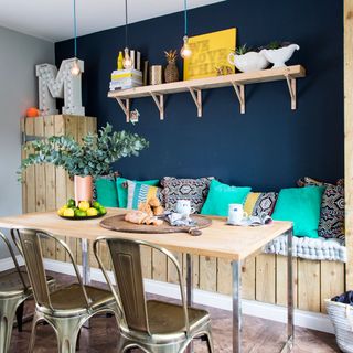 dining area with blue wall and wooden shelf and ceiling lights and dining table and chair and cushions