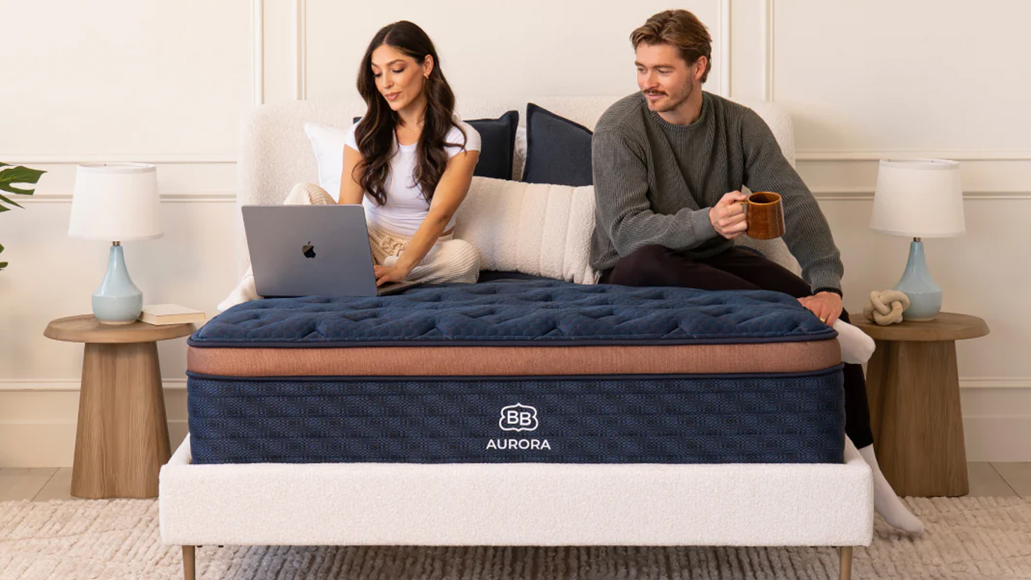 Couple sits on a Brooklyn Bedding Aurora Luxe Mattress