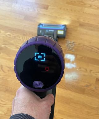 Close-up of the Shark Cordless PowerDetect control panel while vacuuming sugar, flour and cereal on a wooden floor