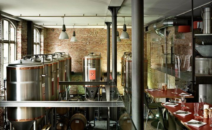 dining tables overlooking a brewery and brewing tanks