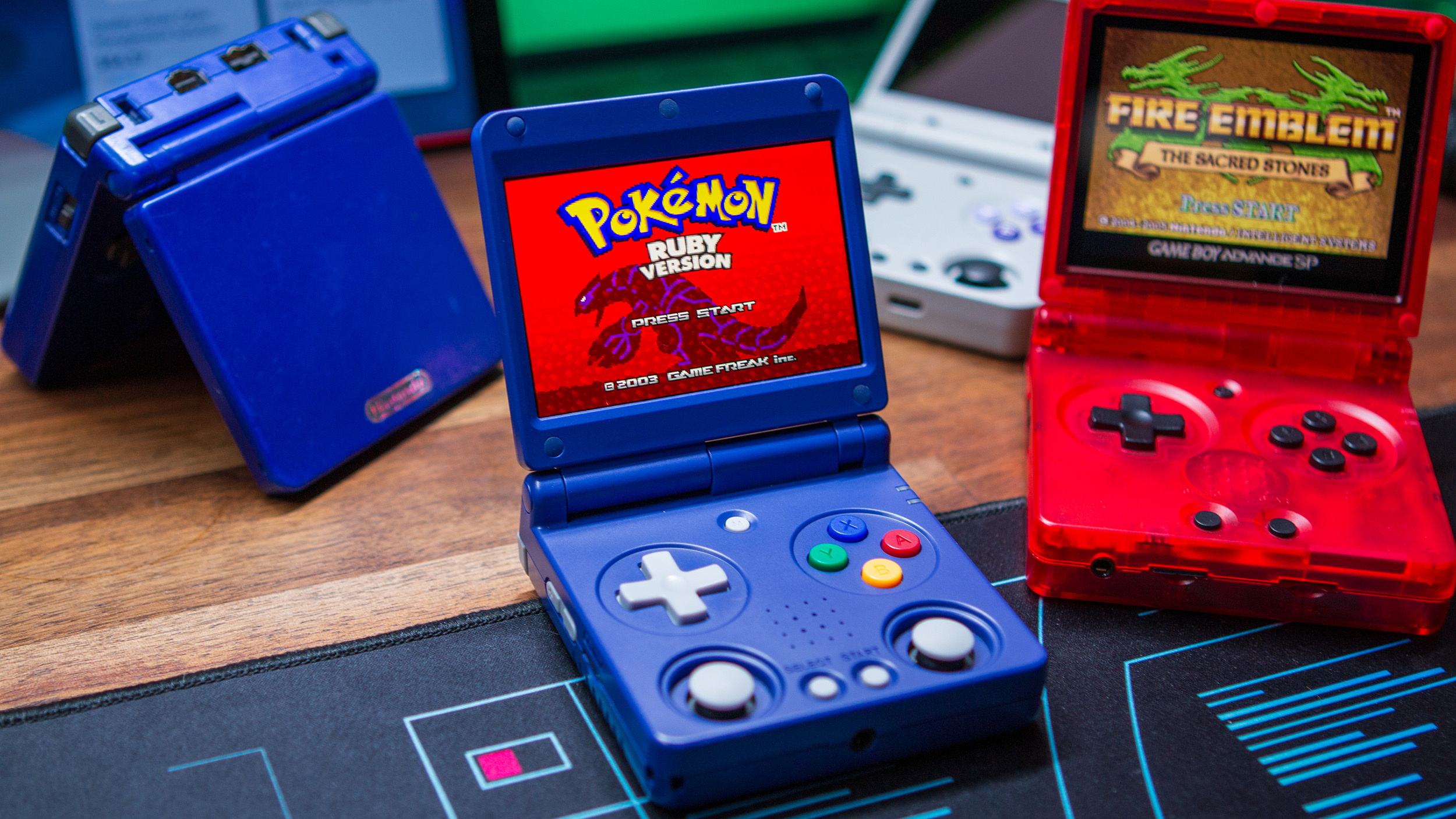 Anbernic RG34XXSP next to RG35XXSP with Game Boy Advance SP and Miyoo Flip in background
