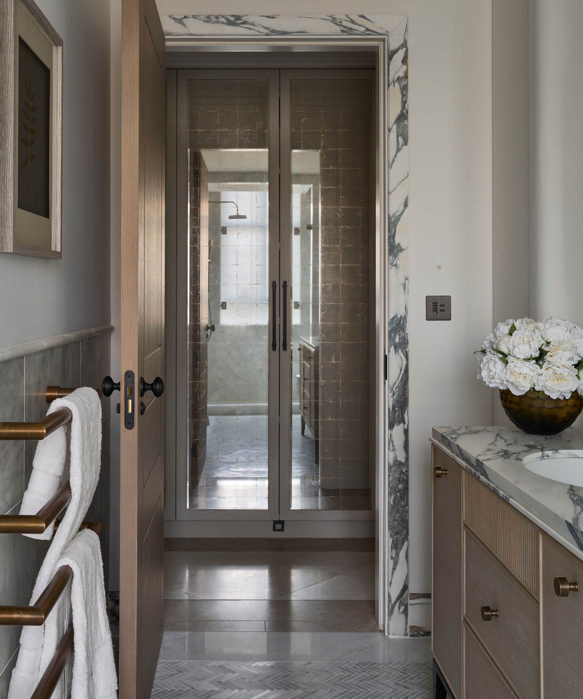 a neutral bathroom with veined marble door trim and a matching marble top sink vanity with oak cabinetry