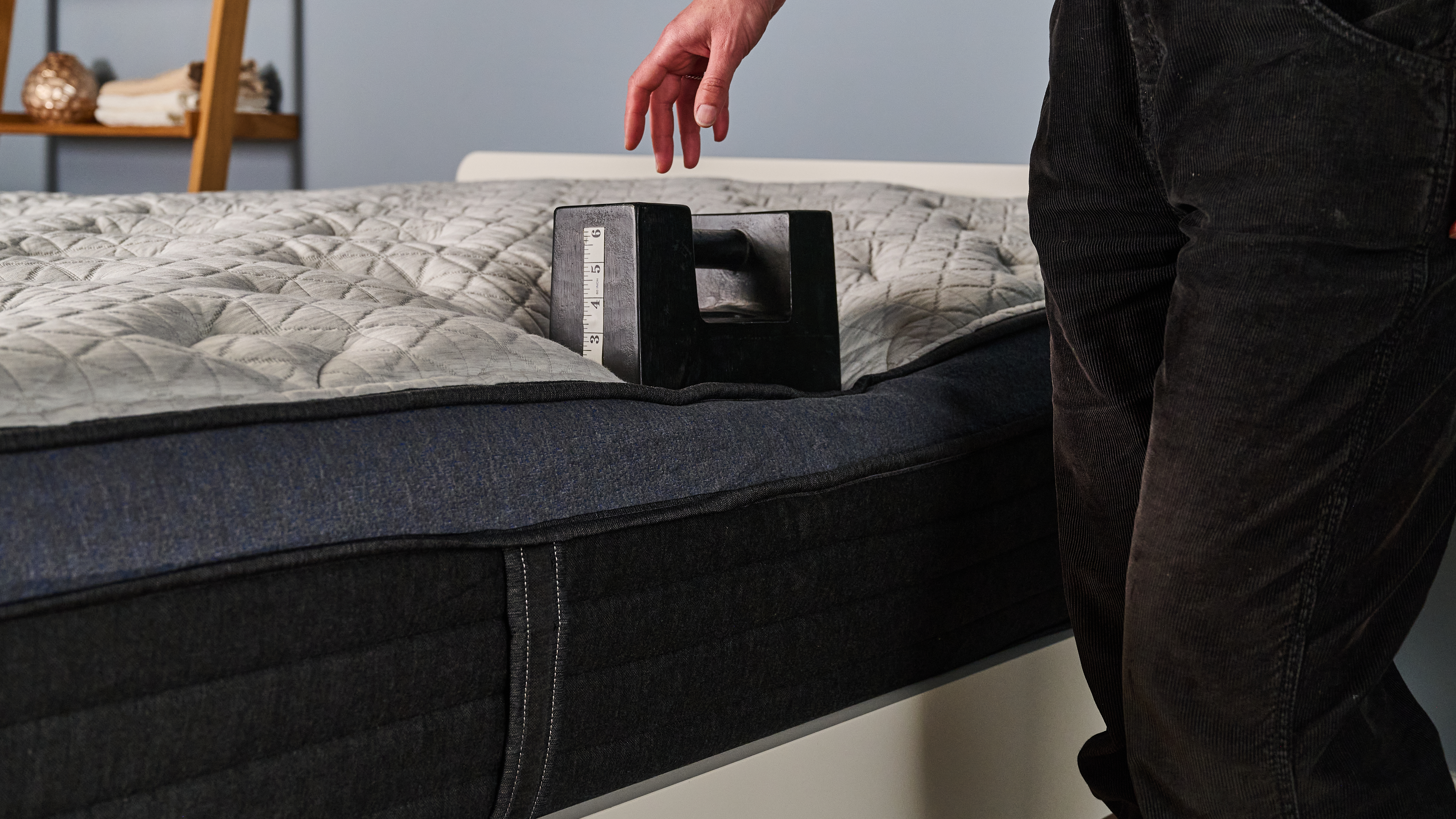 The image shows a mattress tester placing a 56lb weight on the edge of the Helix Midnight Luxe to test its edge support