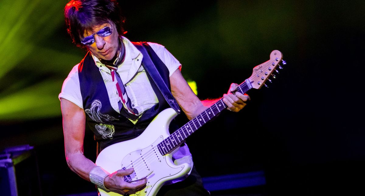 Jeff Beck wears mirrored aviators and plays his white Strat with the reversed neck