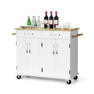 A white kitchen utility cart with cabinets and drawers and a light wooden surface with wine bottles and glasses on top