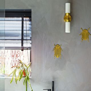 Grey limewashed bathroom, gold sconce and wall decor, window