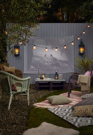 Outdoor cinema with projector and green garden chair with moody lighting