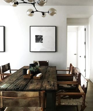 white dining room with retro globe pendant, rustic table and chair, modern black and white artwork