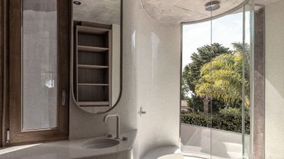 A minimalist stone bathroom with wood accents, a shower room, a rain shower fixture, and a floor length window with a view of nature