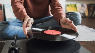 How to clean vinyl records: Man holding vinyl and placing on a turntable