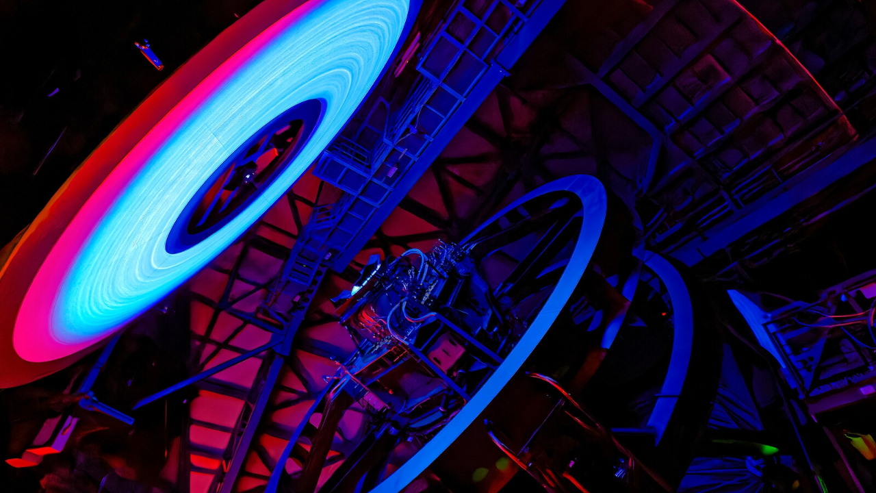 A giant ring of light illuminates a series of metal parts in a giant telescope