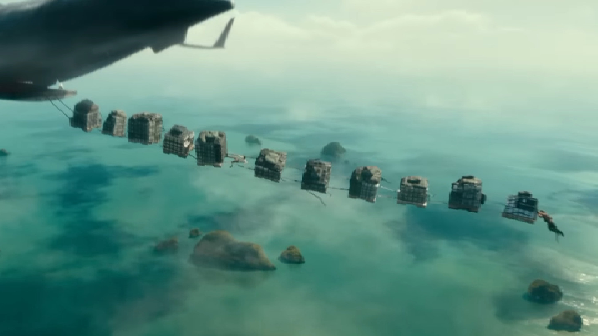 A still from the Uncharted movie, showing several pallets of wares strung together out the back of an airplane in flight