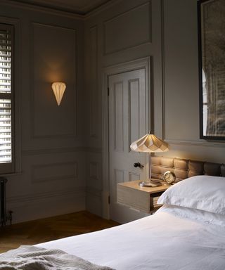 A neutral bedroom with decorative white wall and bedside lamps