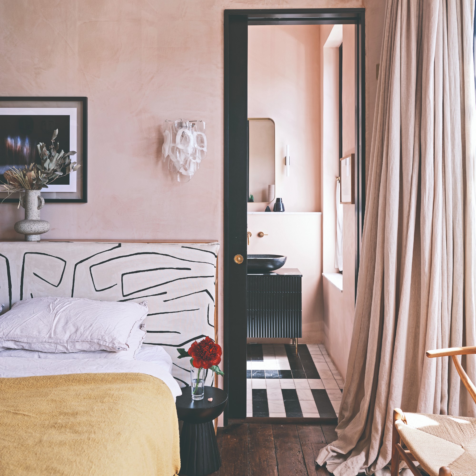 A pink-painted bedroom with tonal pink curtains and an artistic headboard