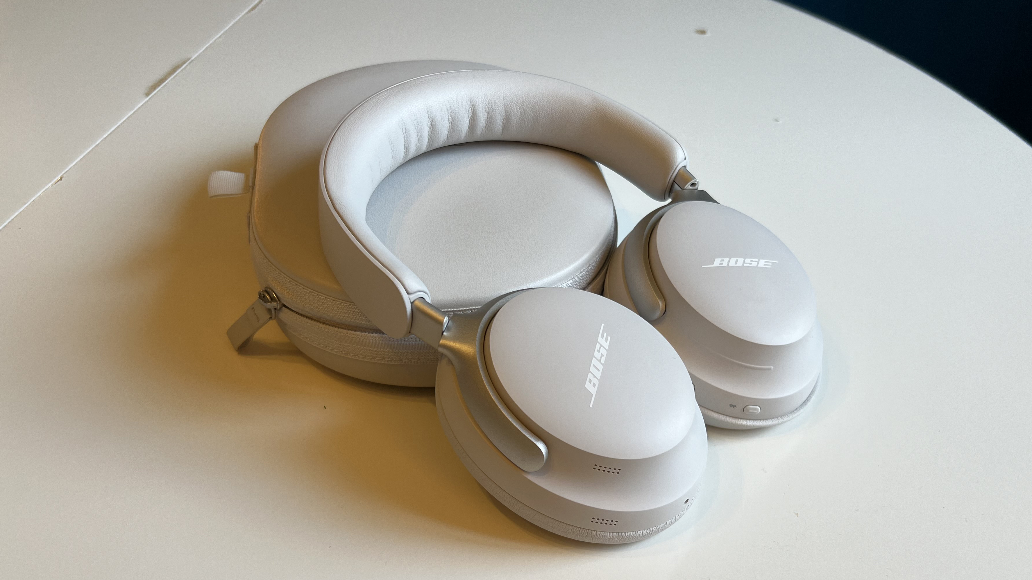 Bose QuietComfort Ultra Headphones on a white table, with their case