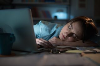 A woman falls asleep at her desk after working 