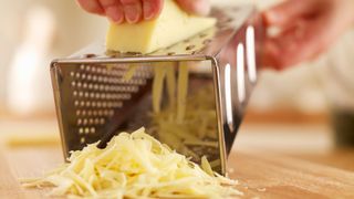 woman grating cheddar with cheese grater
