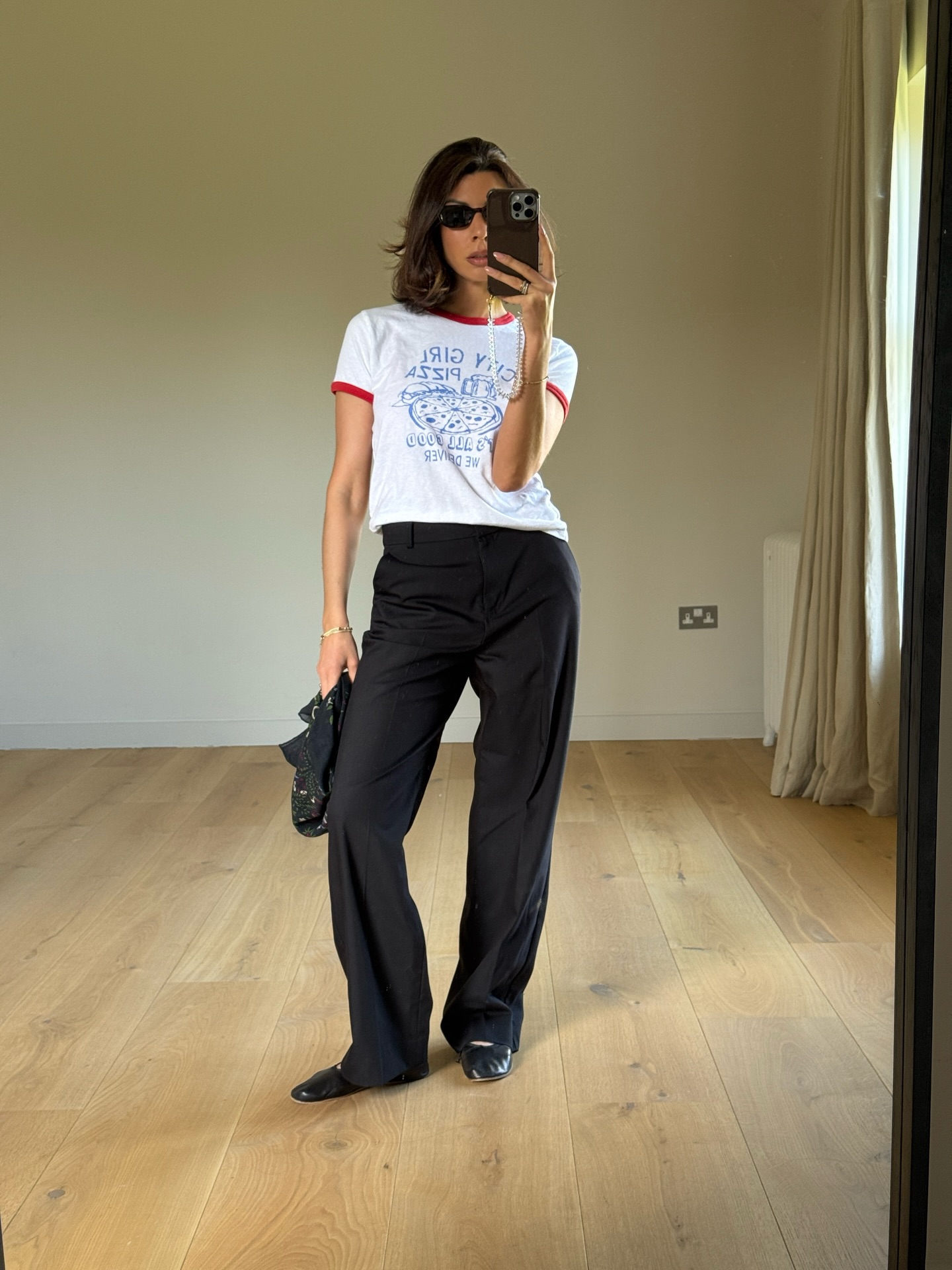 Marianne wearing a slogan baby tee with black trousers, black ballet flats and sunglasses