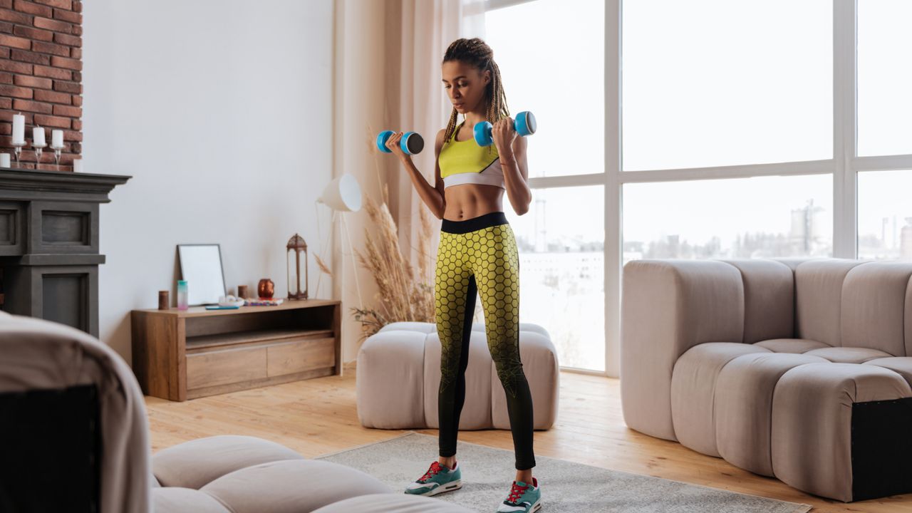 A woman performing a dumbbell curl and press at home