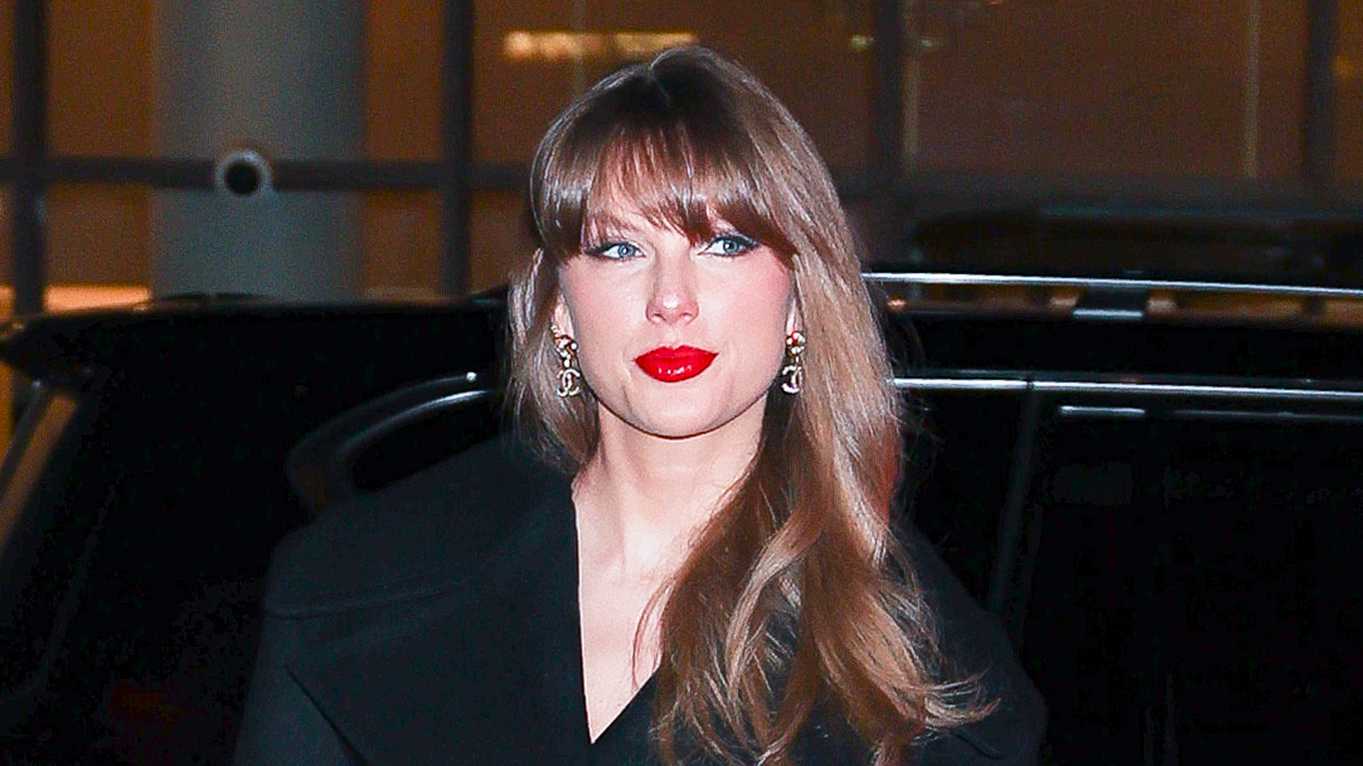 Taylor Swift wearing a black outfit and red lipstick