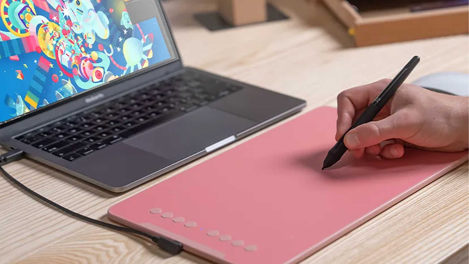 A person draws on a pink drawing tablet